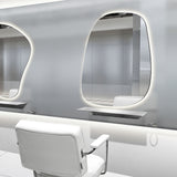 メタリックカラー美容室にあるシルバー色の壁付L型棚とウォールミラーとスタイリングチェア