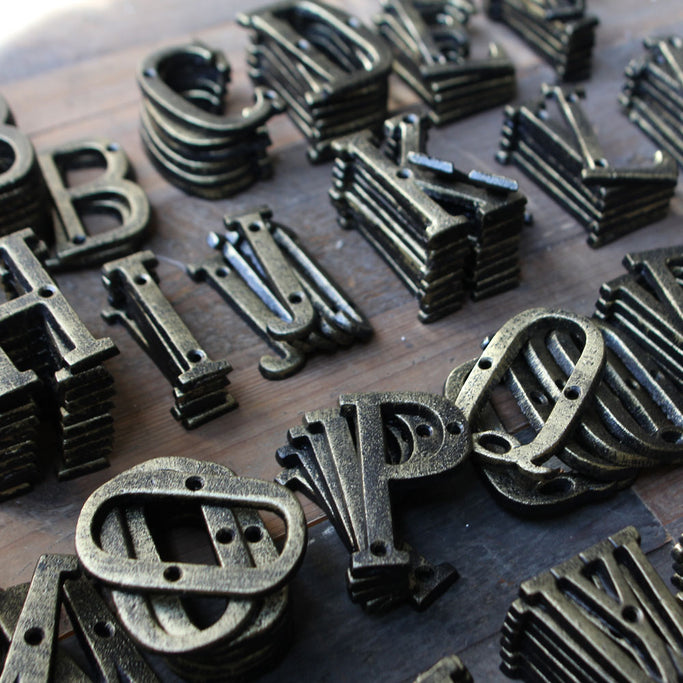 ブロンズ色アルファベットオブジェがウッドテーブルに重なっている